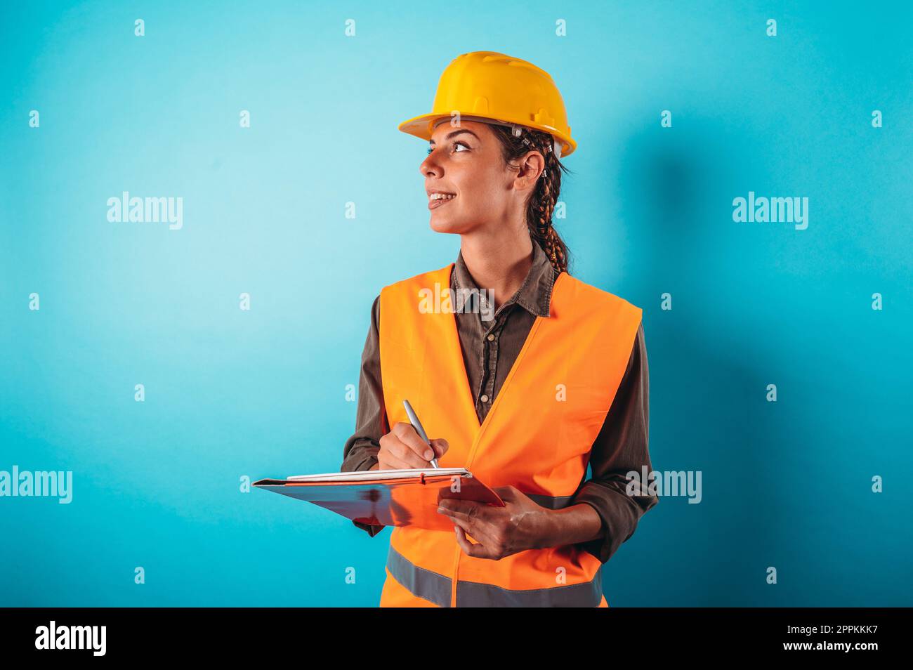 Selbstbewusste Architektin mit orangefarbenem Helm zeichnet eine Zeichnung Stockfoto