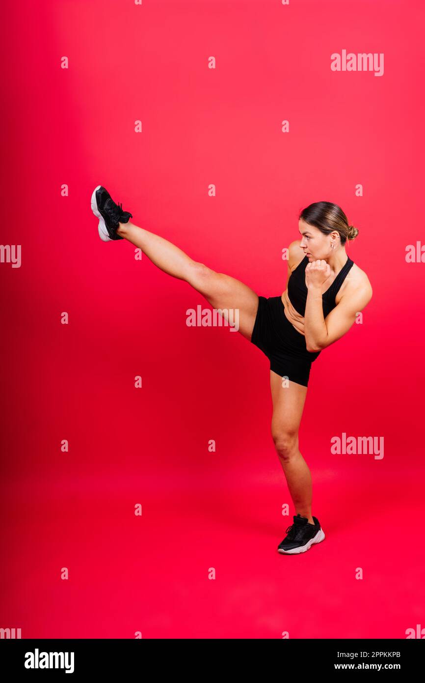 Frau macht High-Kick, Tae-bo. Sportliche Passform für Damen mit perfektem Körperkick und Schlägen mit den Beinen Stockfoto
