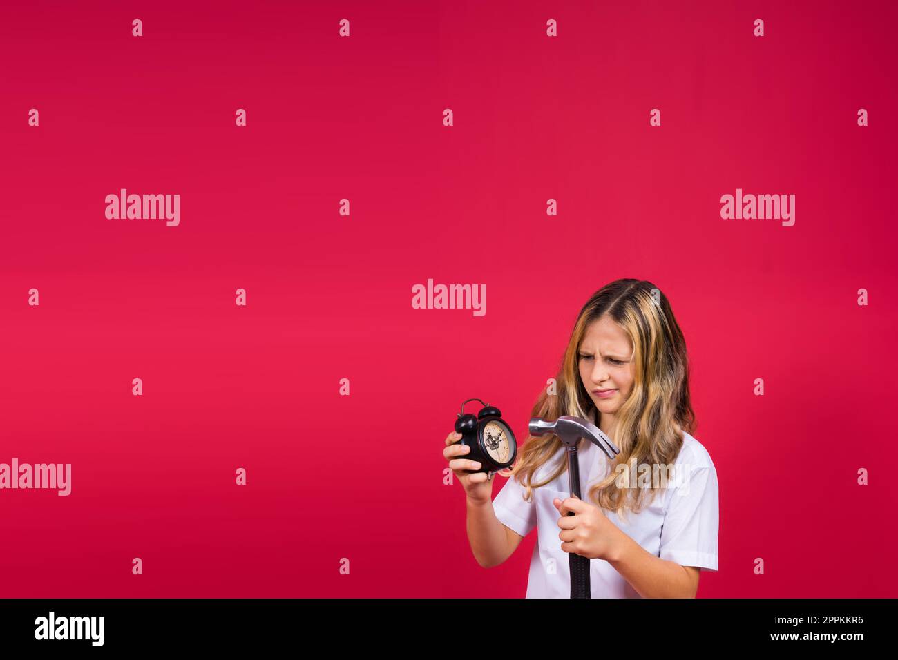 Ein Mädchen hält einen Hammer und lächelt mit einem fröhlichen und coolen Lächeln im Gesicht. Zähne zeigen. Stockfoto