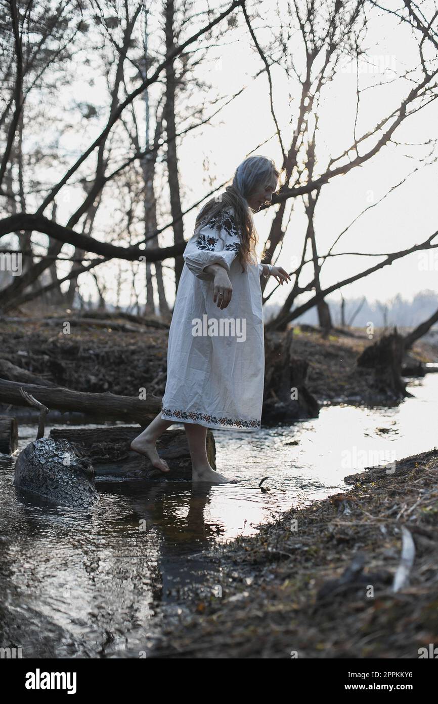 Frau in ukrainischem Folklorekleid, die auf einer malerischen Wasserfotografie spaziert Stockfoto