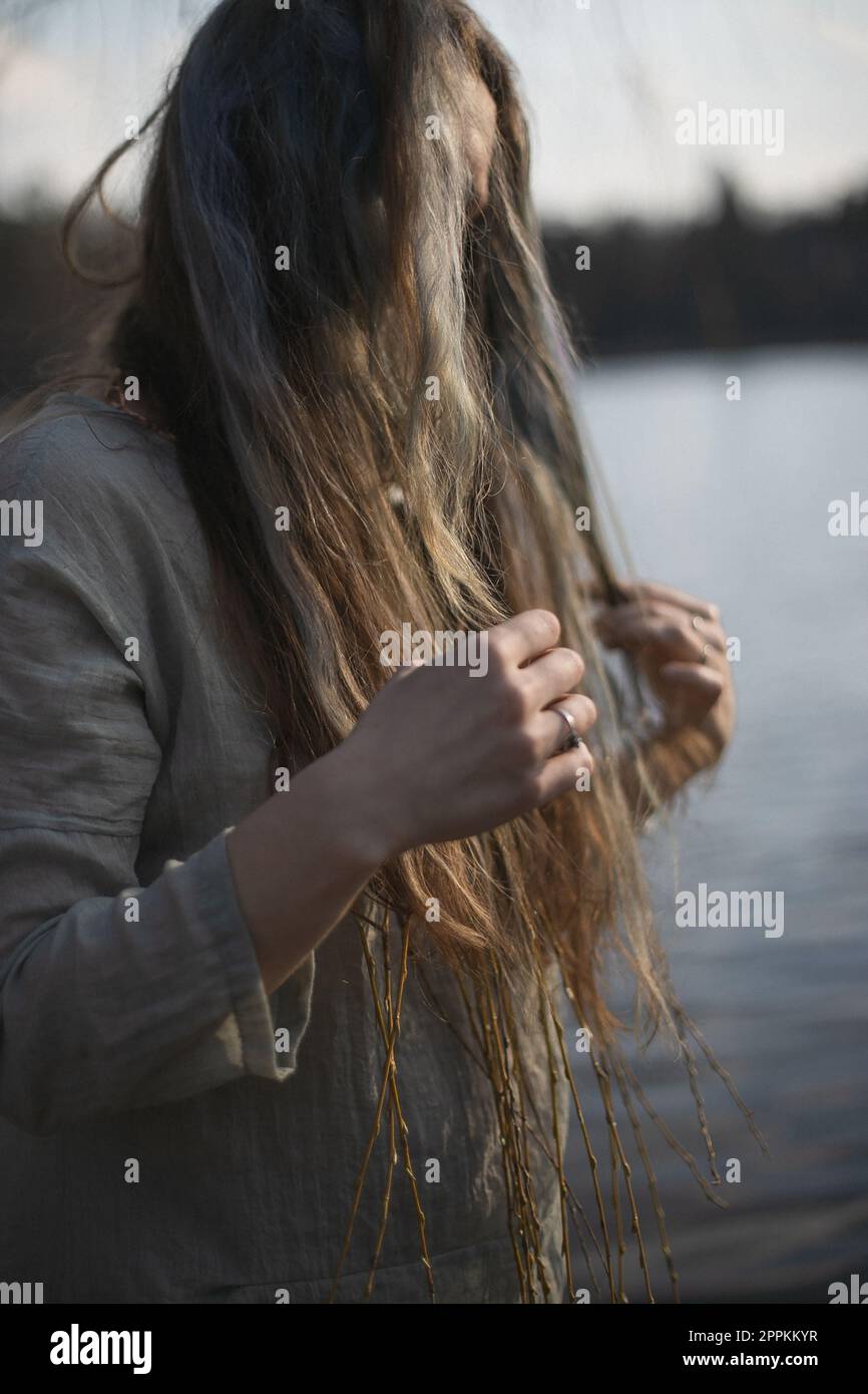 Nahaufnahme Frau in Leinenbekleidung berührt Stränge von graubraunem Haar Porträtbild Stockfoto