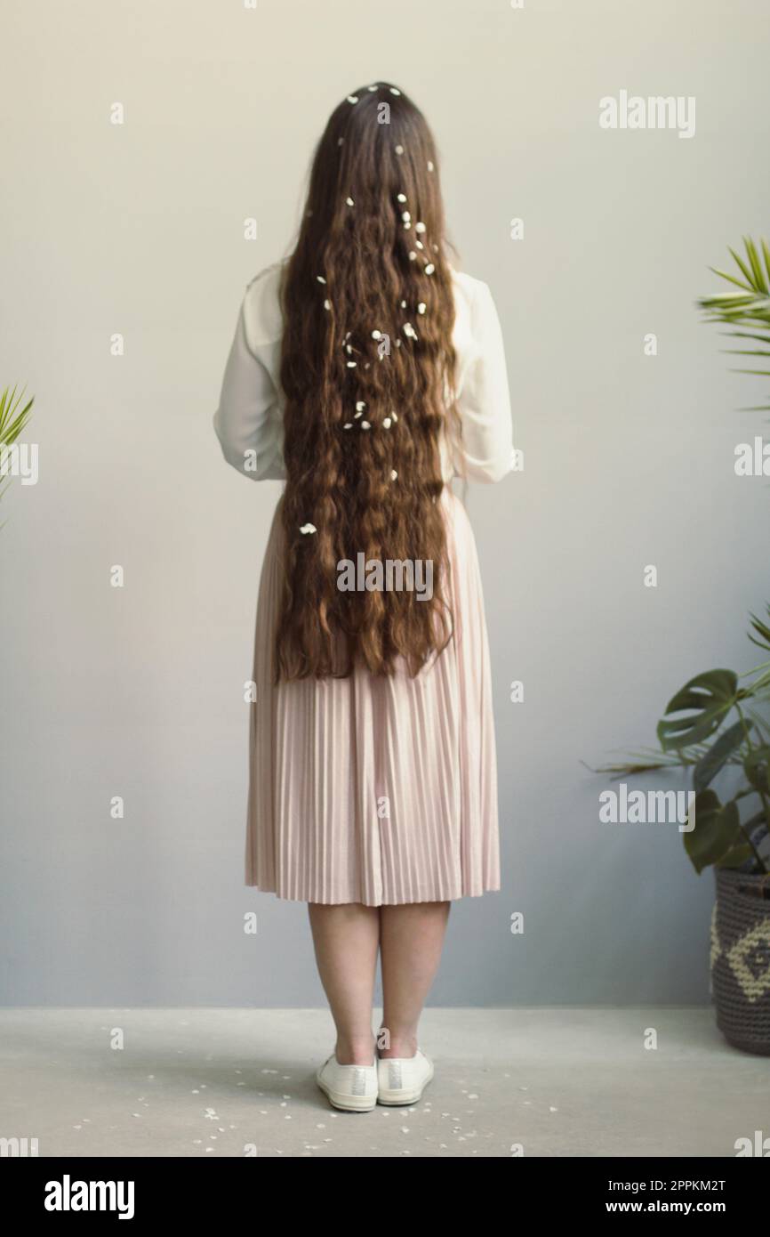Nahaufnahme einer jungen Frau mit weißen Blütenblättern in einem langen Haar Konzeptfoto Stockfoto