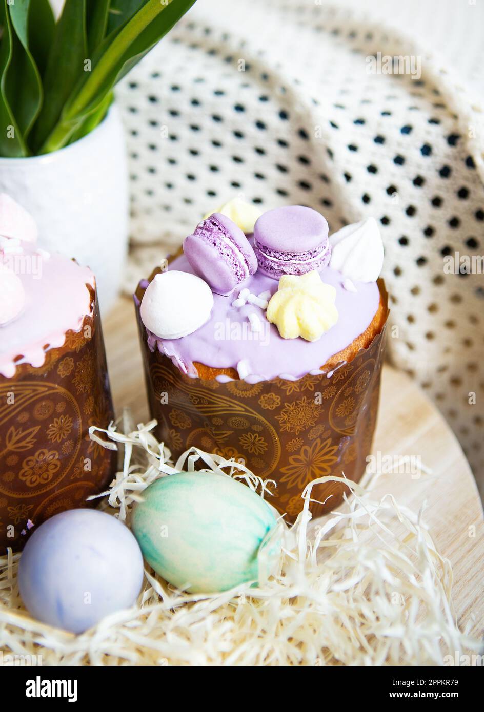 Farbenfrohe Ostereier liegen zusammen mit Ostergebäck mit bunter Schokolade auf einem Holztisch. Stockfoto