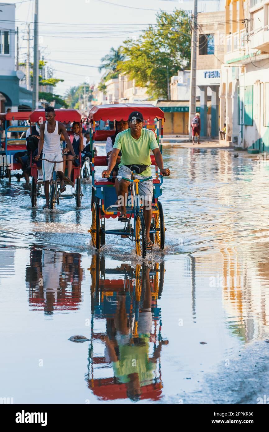 Ein traditionelles Rikscha-Fahrrad mit madagassischen Einwohnern auf der Straße von Toliara, eine der Möglichkeiten, Geld zu verdienen. Das Alltagsleben auf der Straße Madagaskars. Stockfoto