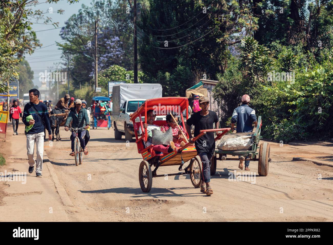 Ein traditionelles Rikscha-Fahrrad mit madagassischen Einwohnern auf der Straße von Antsirabe, eine der Möglichkeiten, Geld zu verdienen. Das Alltagsleben auf der Straße Madagaskars. Stockfoto