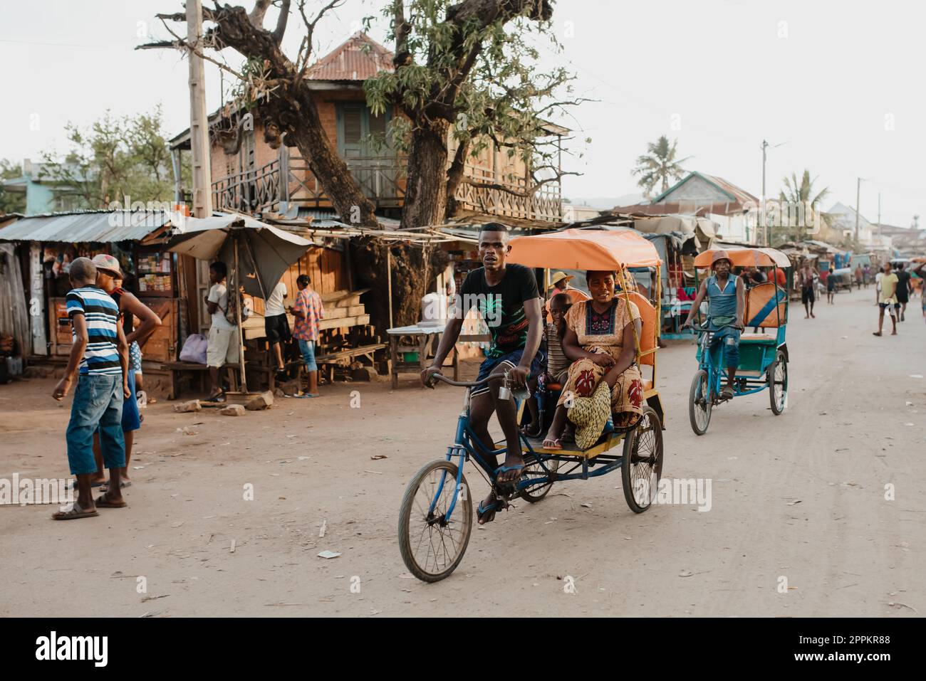Ein traditionelles Rikscha-Fahrrad mit madagassischen Einwohnern auf der Straße von Miandrivazo, eine der Möglichkeiten, Geld zu verdienen. Das Alltagsleben auf der Straße Madagaskars. Stockfoto