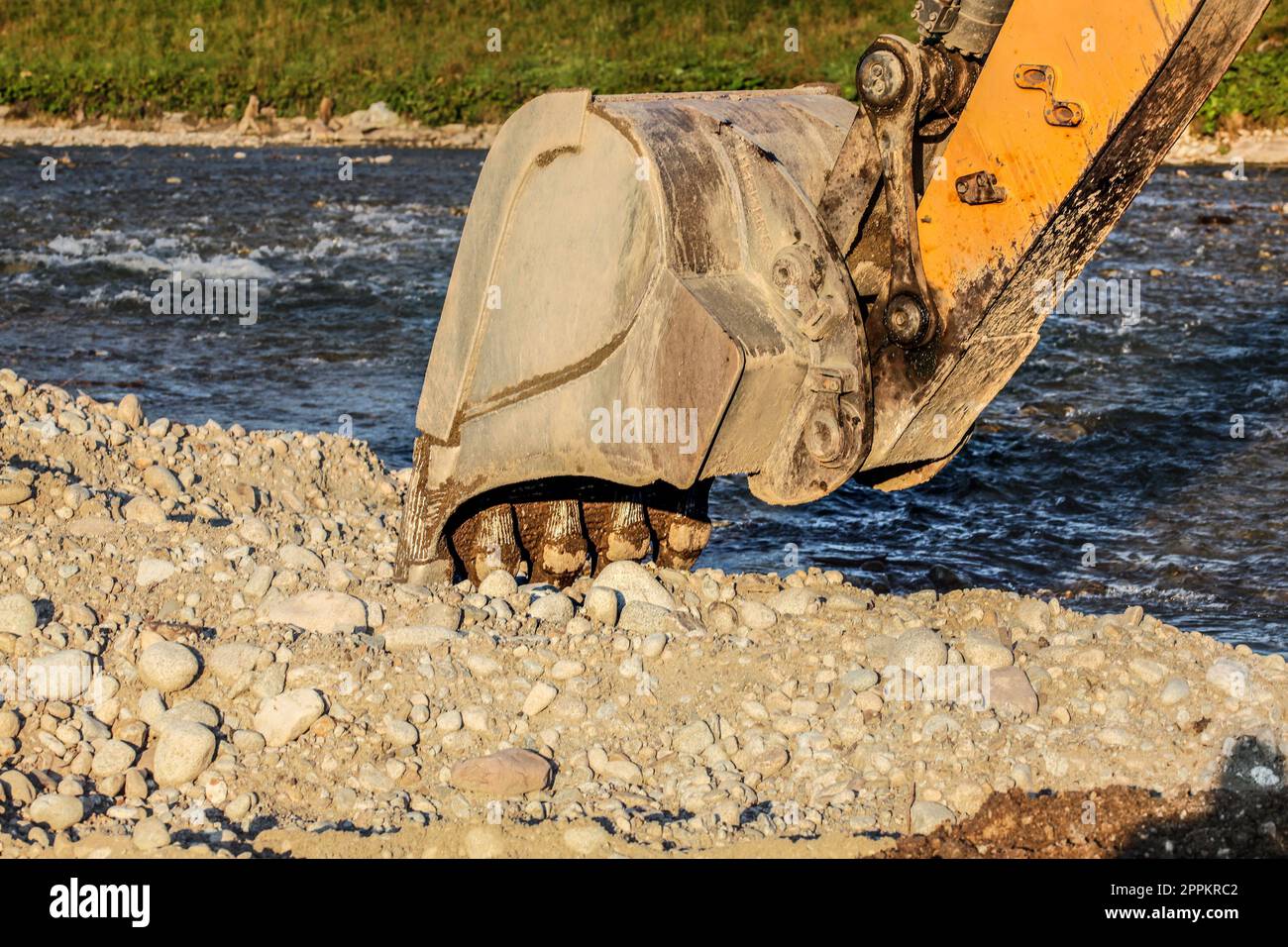 Gelber Bagger (Bagger) Schaufel Graben in Steine Boden am Fluss. Stockfoto