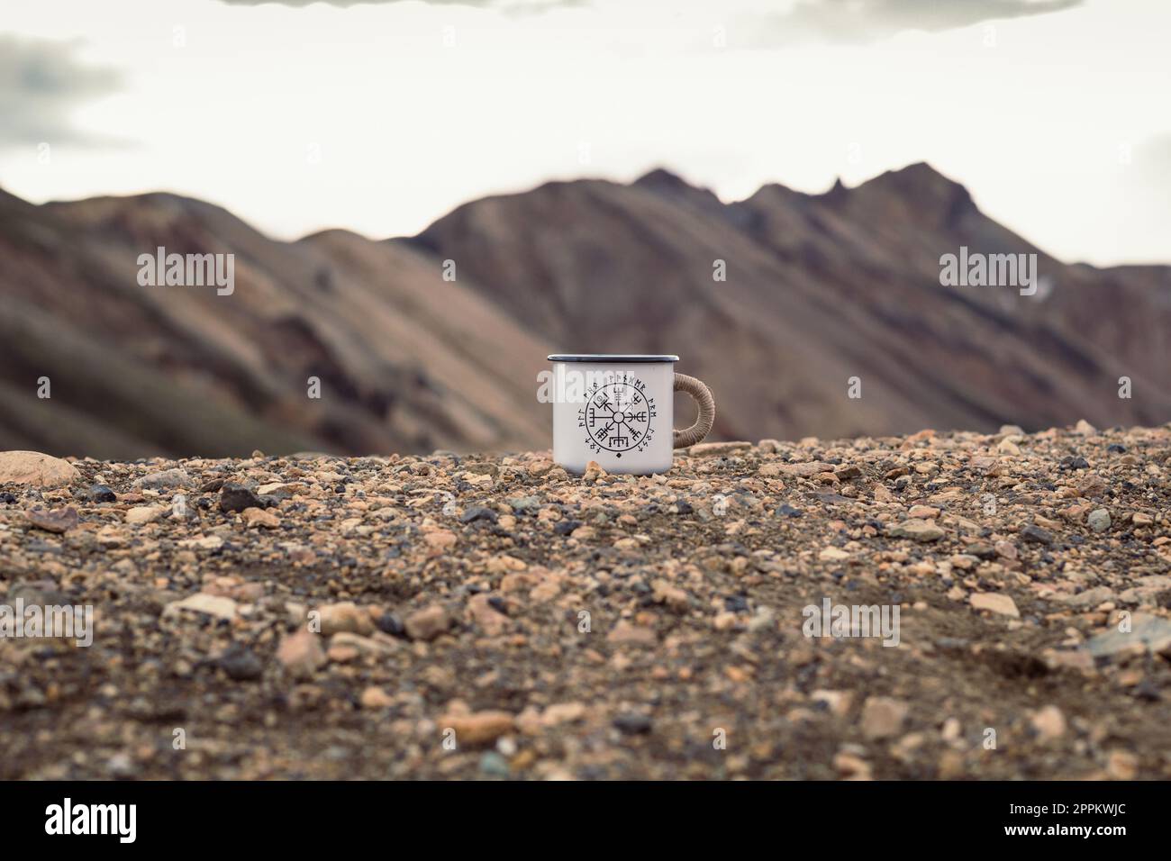 Nahaufnahme des emaillierten Bechers auf dem Konzeptfoto aus Kieselstein Stockfoto