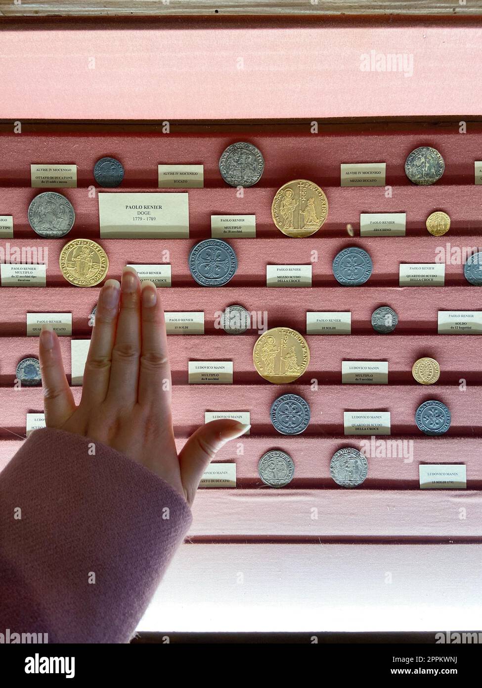 Die Hand greift nach einem Schaukasten mit mittelalterlichen Münzen Stockfoto