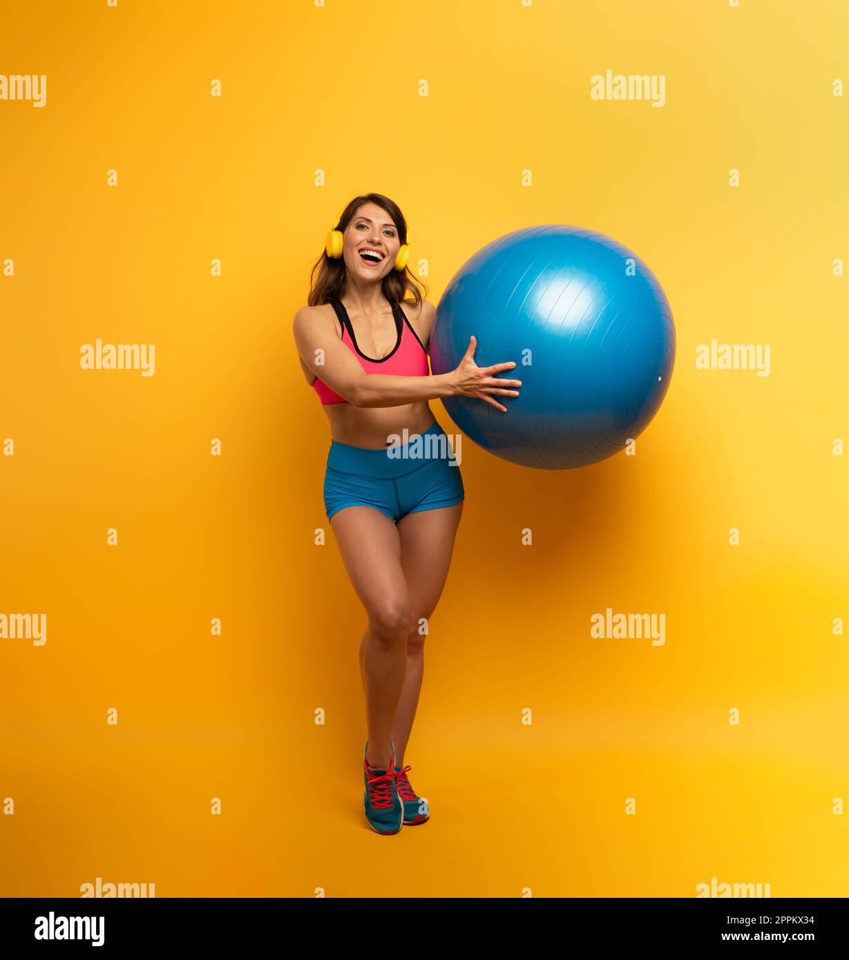 Mädchen mit Gymnastikball und Headset ist bereit zu starten Fitnessaktivitäten Stockfoto