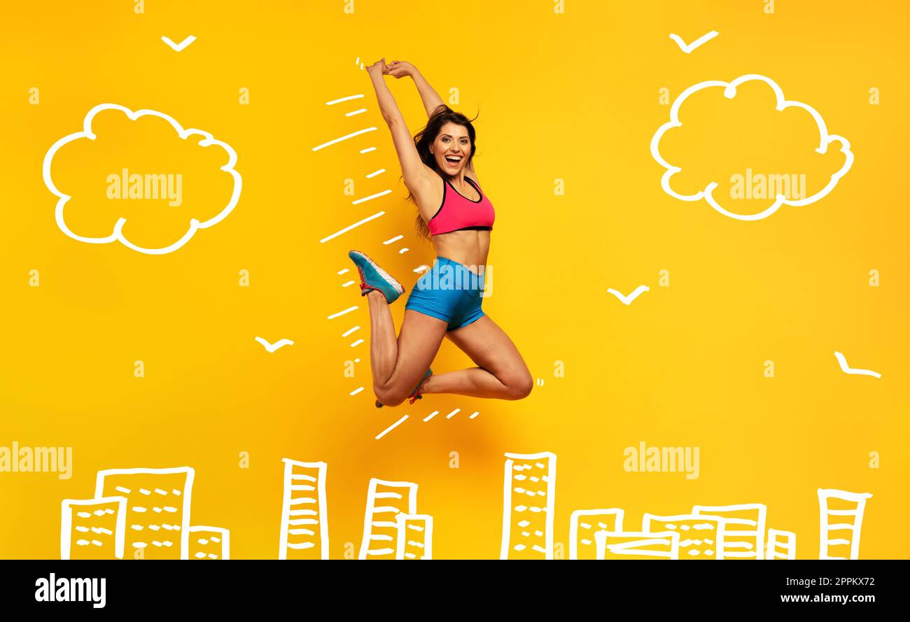 Sportfrau springt auf gelbem Hintergrund. Fröhlicher und fröhlicher Ausdruck. Stockfoto