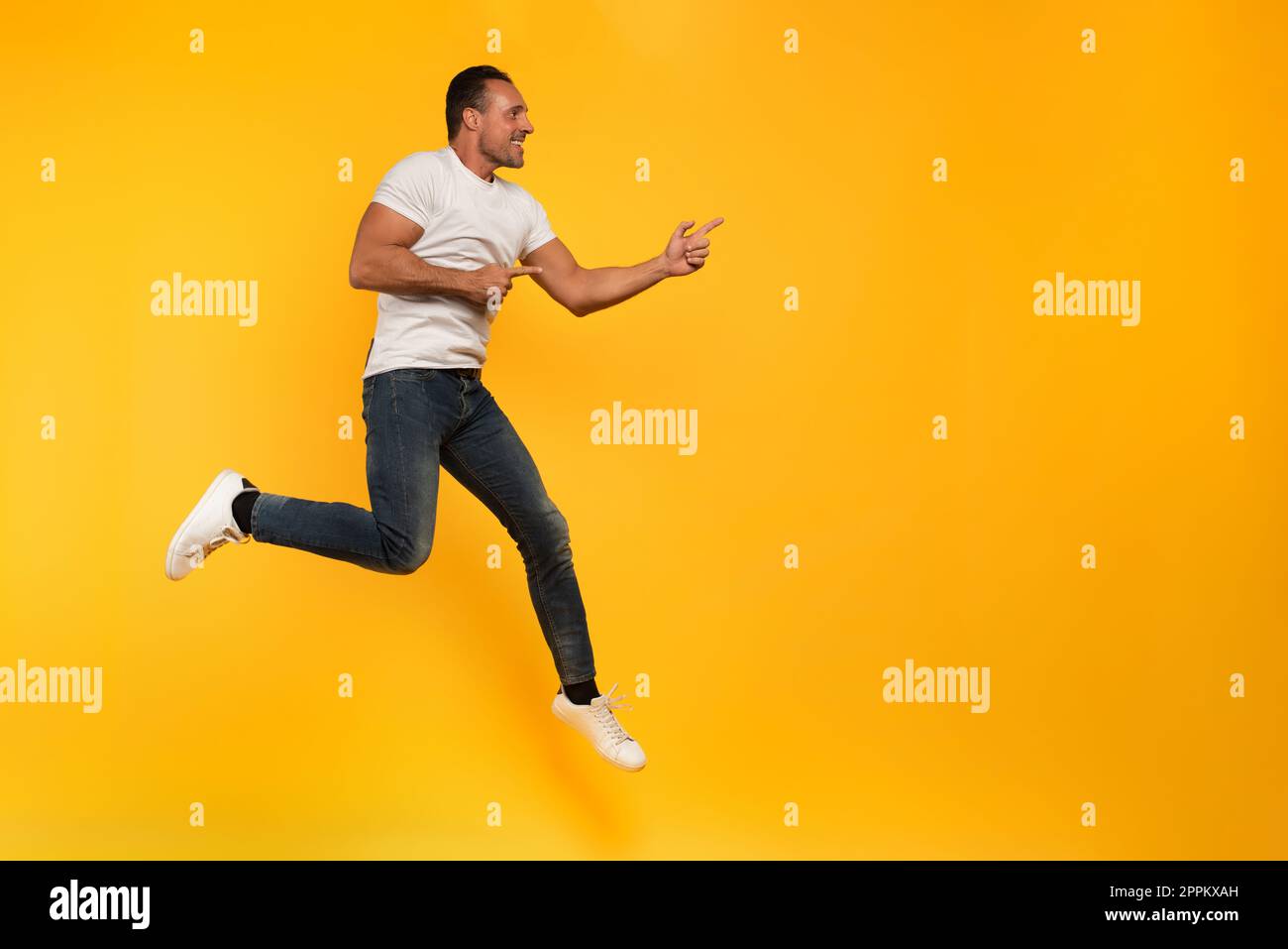 Sport Mann springt auf gelbem Hintergrund. Froh und glücklich. Stockfoto