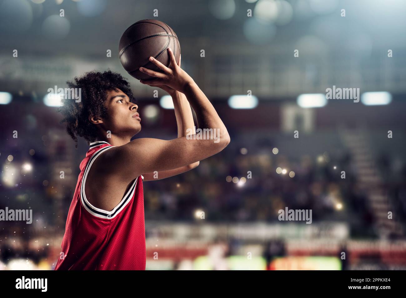 Der Basketballspieler wirft den Ball im Stadion voller Zuschauer in den Korb Stockfoto