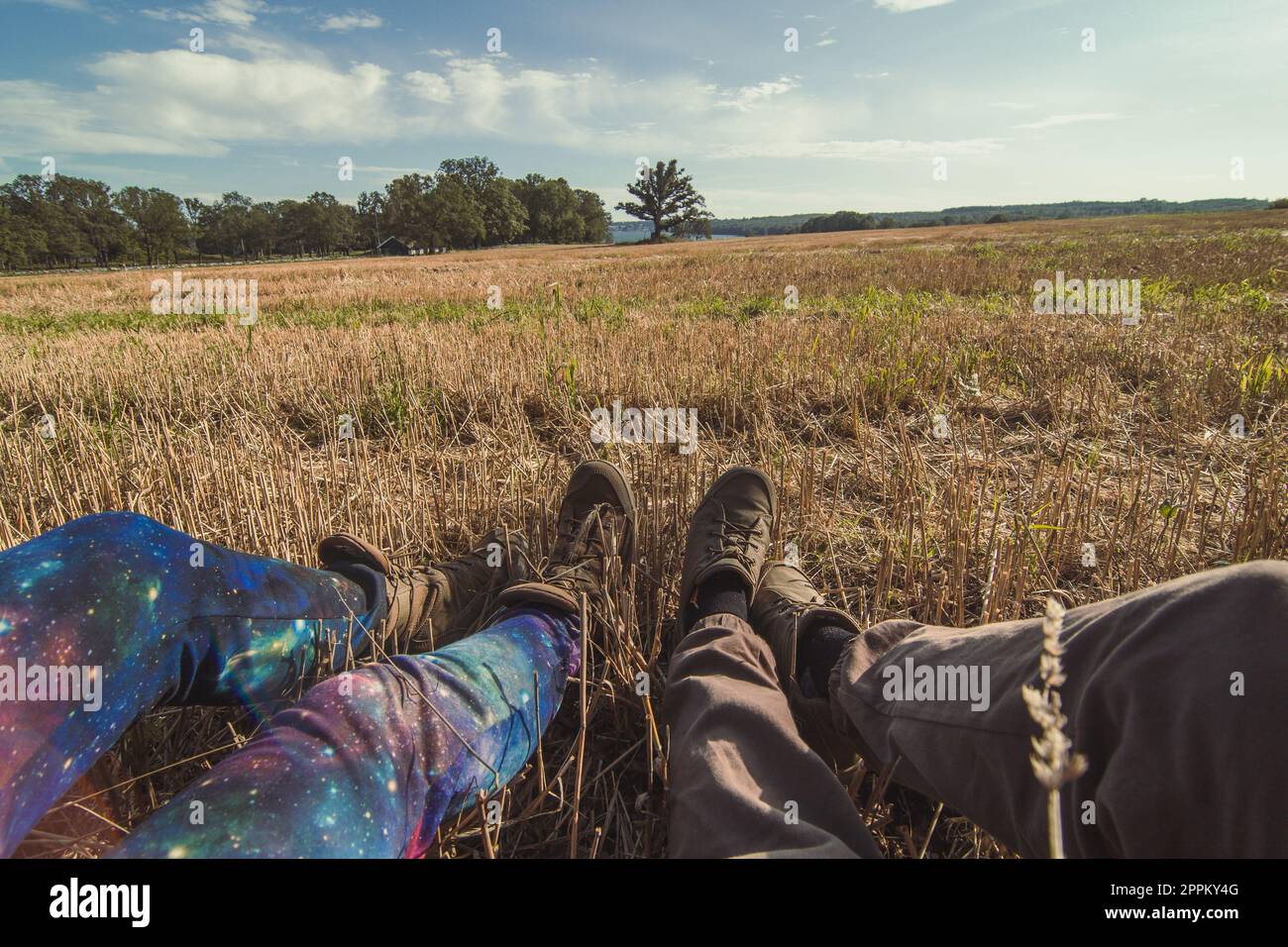 Touristen aus nächster Nähe, die sich auf der Wiese mit einem Konzeptfoto aus gemähtem Gras ausruhen Stockfoto
