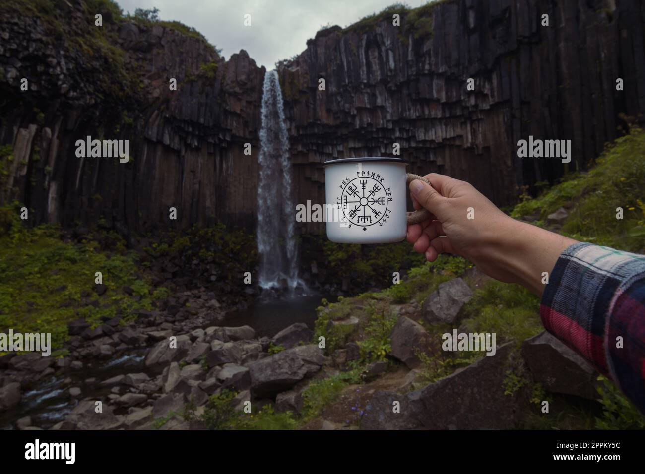 Nahaufnahme der Touristenvorführung – Tasse vor Wasserfall – Konzeptfoto Stockfoto