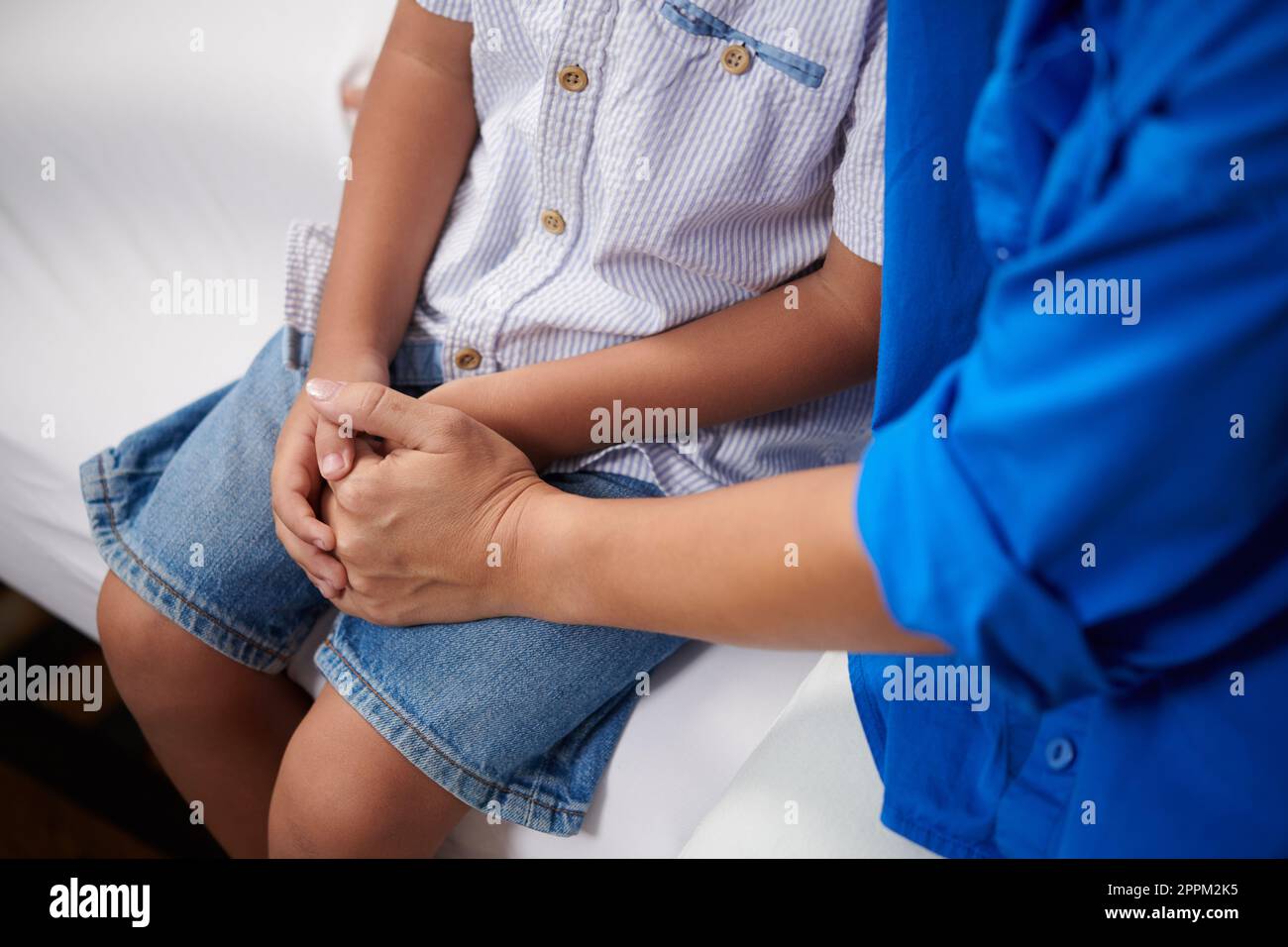 Die Mutter hält die Hände des kleinen Sohnes, wenn der Arzt die Diagnose sagt Stockfoto