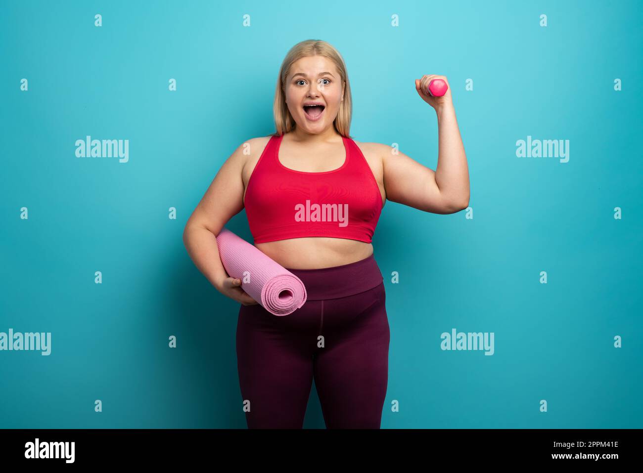 Fat Girl macht zu Hause Fitness-Studio. Zufriedener Ausdruck. Hintergrund Zyan Stockfoto