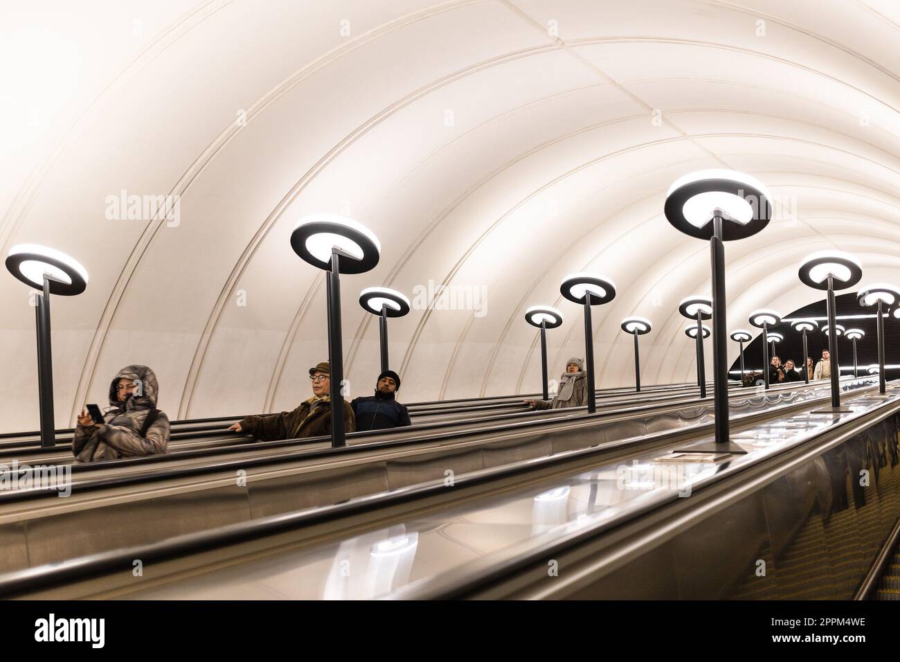 Passagiere steigen mit einer langen Rolltreppe in die U-Bahn Stockfoto