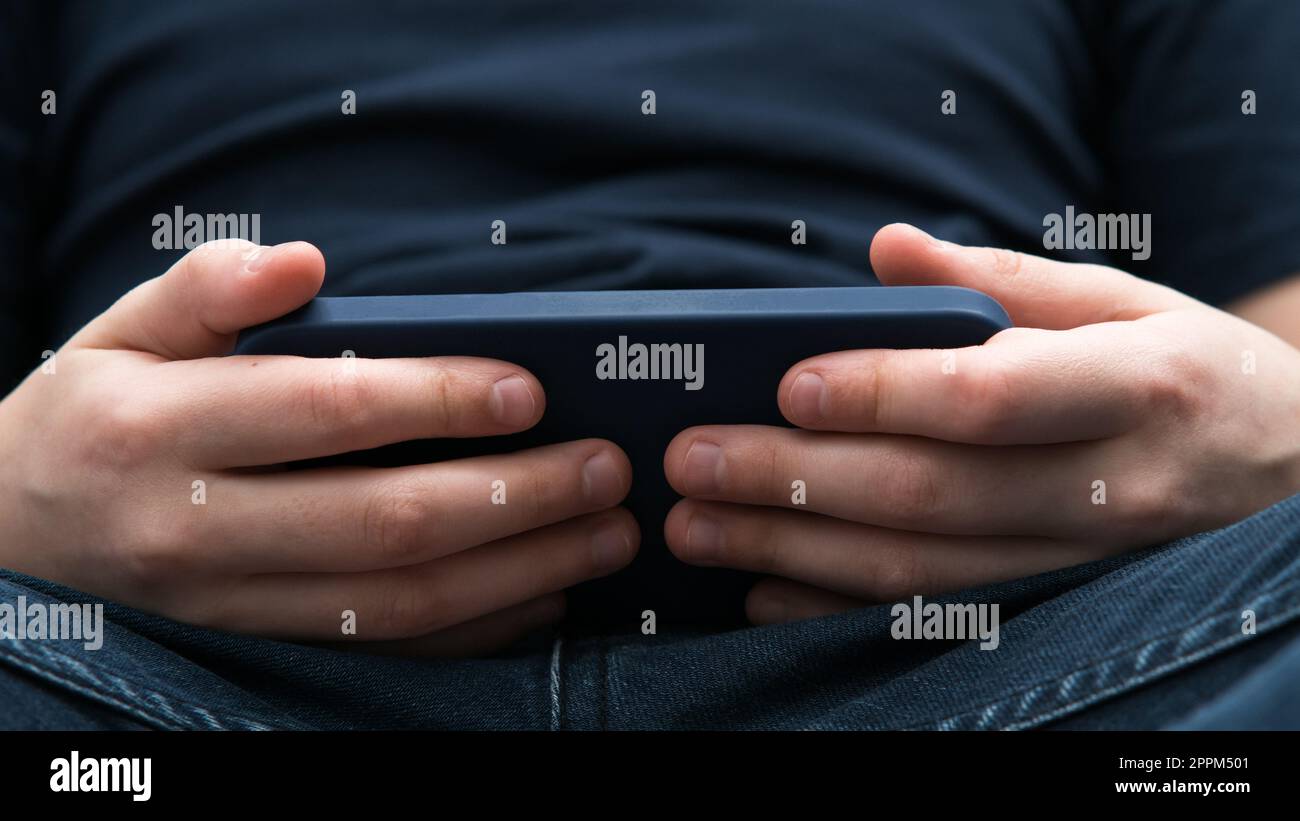 Männliche Hände spielen Videospiele auf Smartphone-Nahaufnahme. Ein Mann, der ein Mobiltelefon benutzt, um ein Spiel zu spielen oder Online-Videoinhalte anzusehen. Stockfoto
