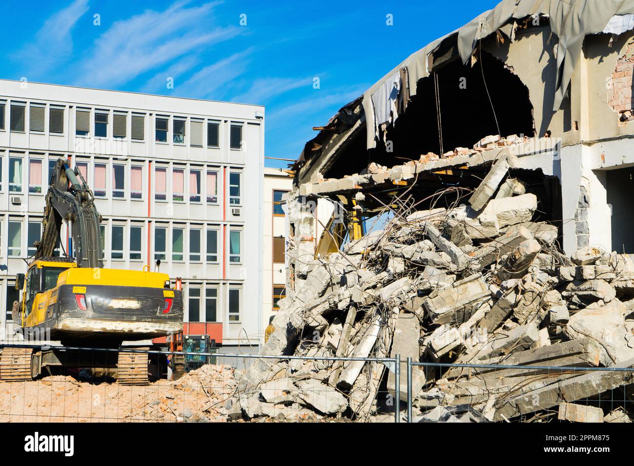 Hintergrund des Abbruchprozesses von Gebäuden. Ein Bagger zerbricht das alte Haus. Stockfoto