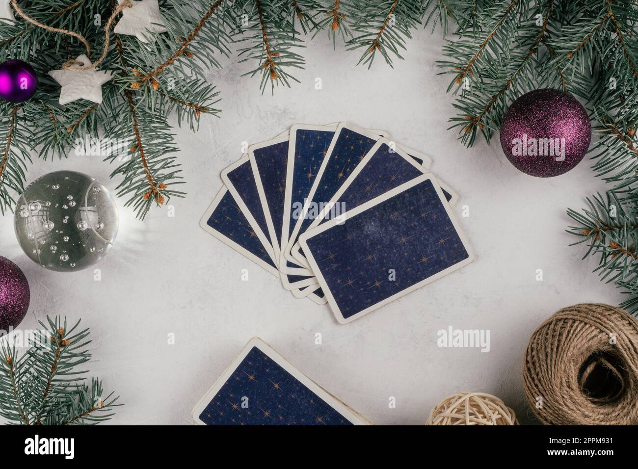 Tarot-Karten, die auf weißem Beton aufgefächert sind, mit Christbaumzweigen und Dekor. Minsk, Belarus, 19.11.2021 Stockfoto