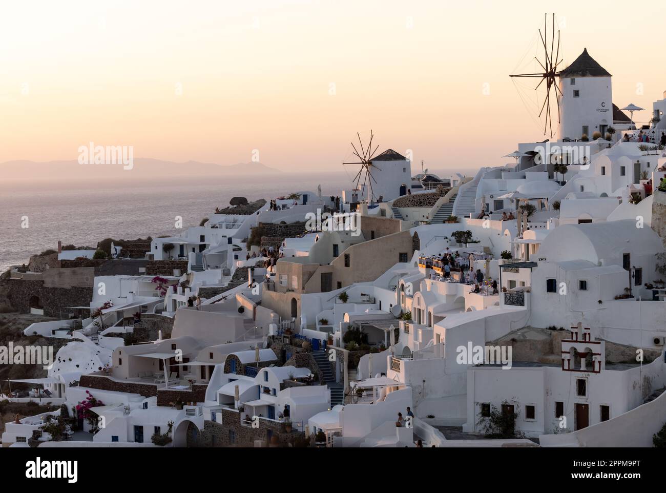 Weiß getünchte Häuser und Windmühlen in Oia in warmen Sonnenstrahlen auf Santorini. Griechenland Stockfoto