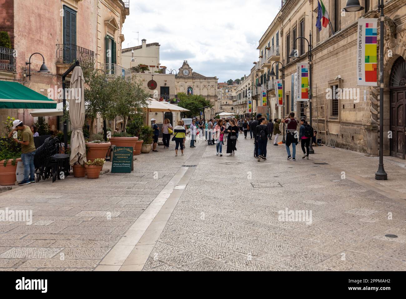 Touristen bei einem Spaziergang auf der kopfsteingepflasterten Straße in der Sassi di Matera, einem historischen Viertel in der Stadt Matera. Stockfoto