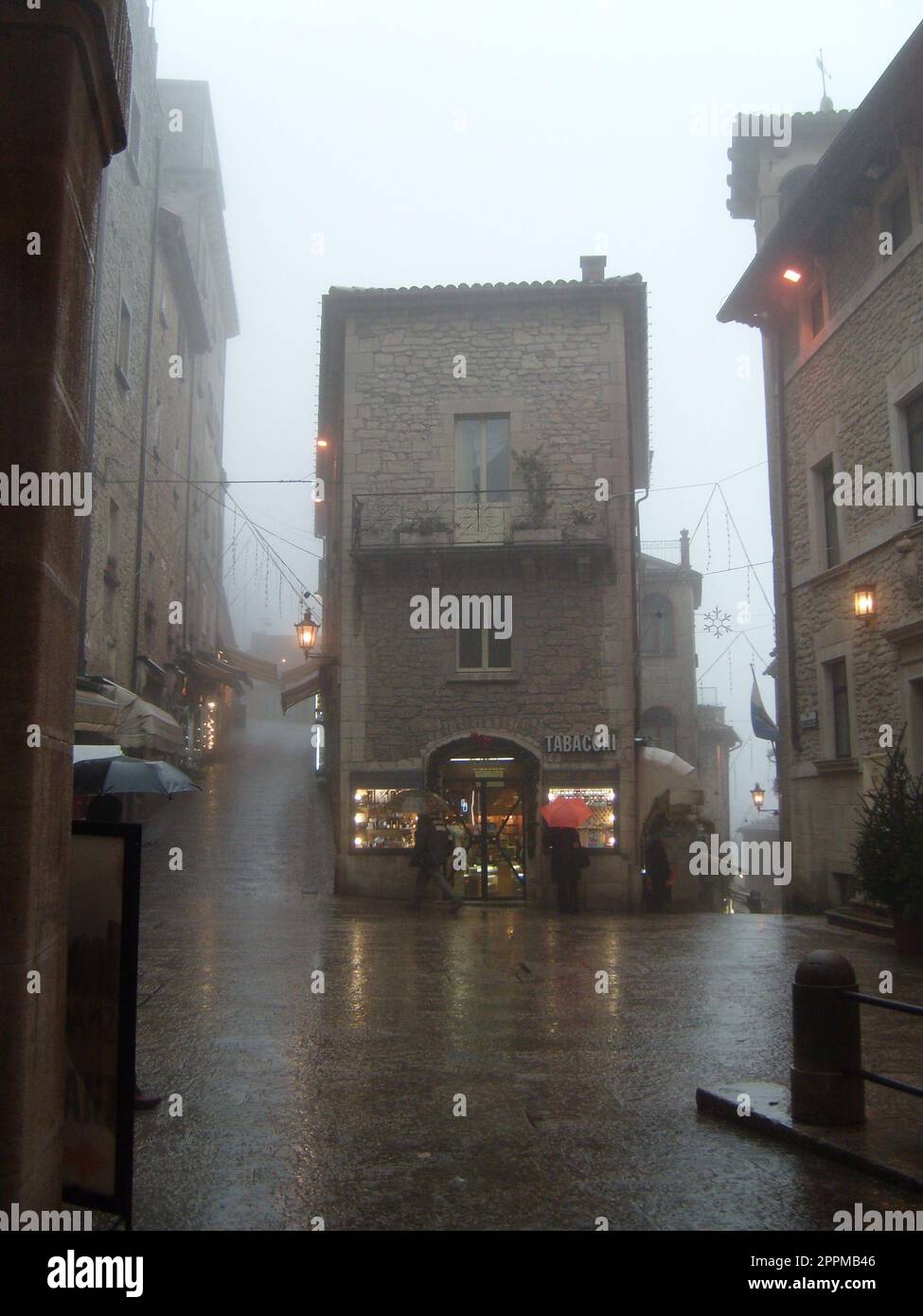 San Marino, 18. Januar 2020. Nebel in San Marino. Schlechte Sicht. Das historische Zentrum von San Marino, der zentrale Platz. Passanten unter Schirmen eilen nach Hause. Stockfoto