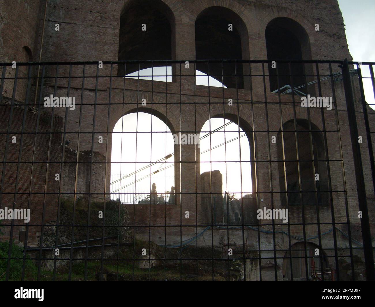 Restaurierung des römischen Kolosseums. Ein Metallzaun um das kolosseum. Die Abendsonne bricht durch hohe Fenster und Öffnungen Stockfoto