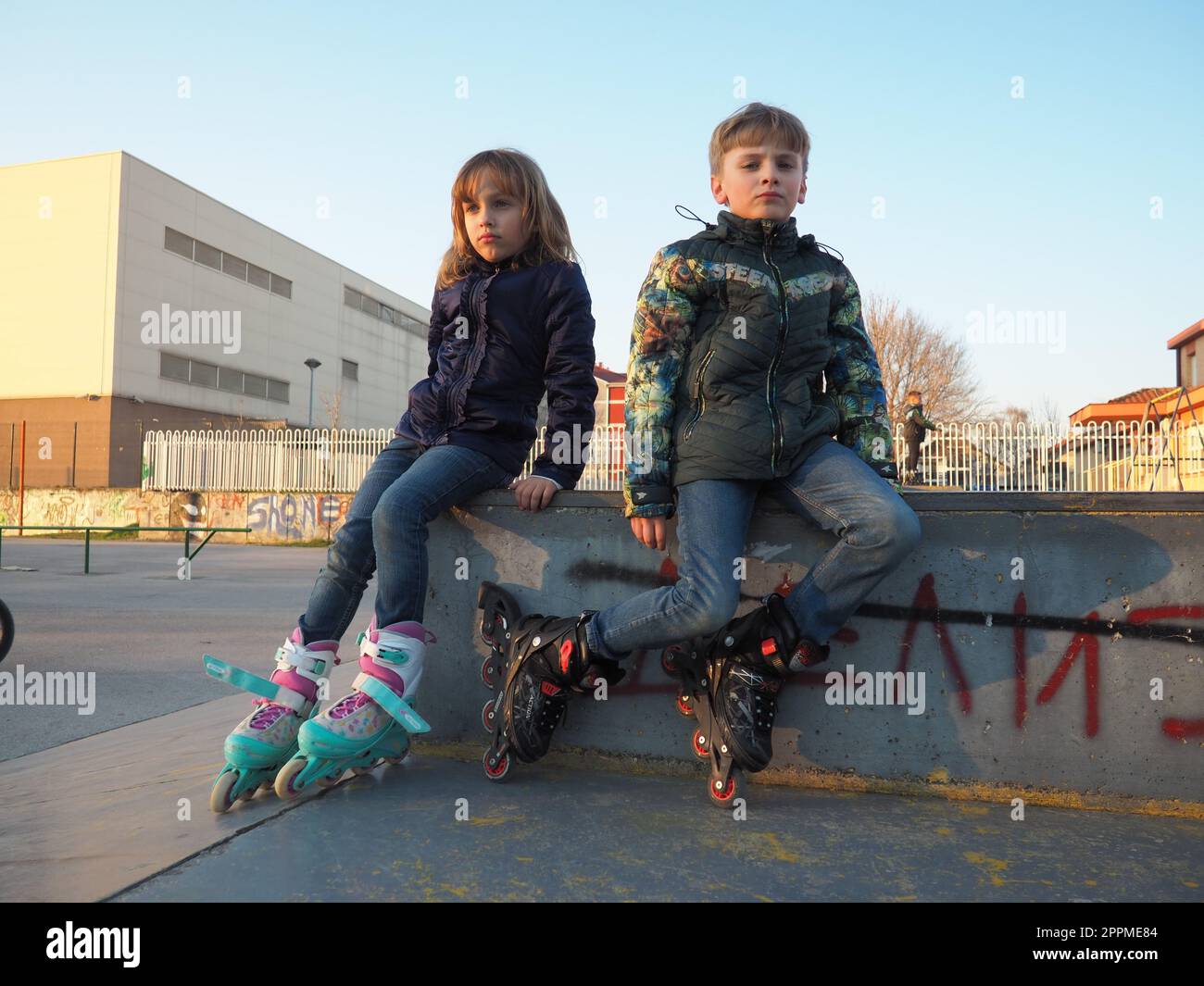 Sremska Mitrovica, Serbien, 7. März 2021. Junge und Mädchen auf Rollschuhen auf dem Sportplatz. Junge und Mädchen im Teenageralter ruhen sich nach dem Rollschuhlaufen aus. Kinder in Demi-Season-Klamotten. Stockfoto