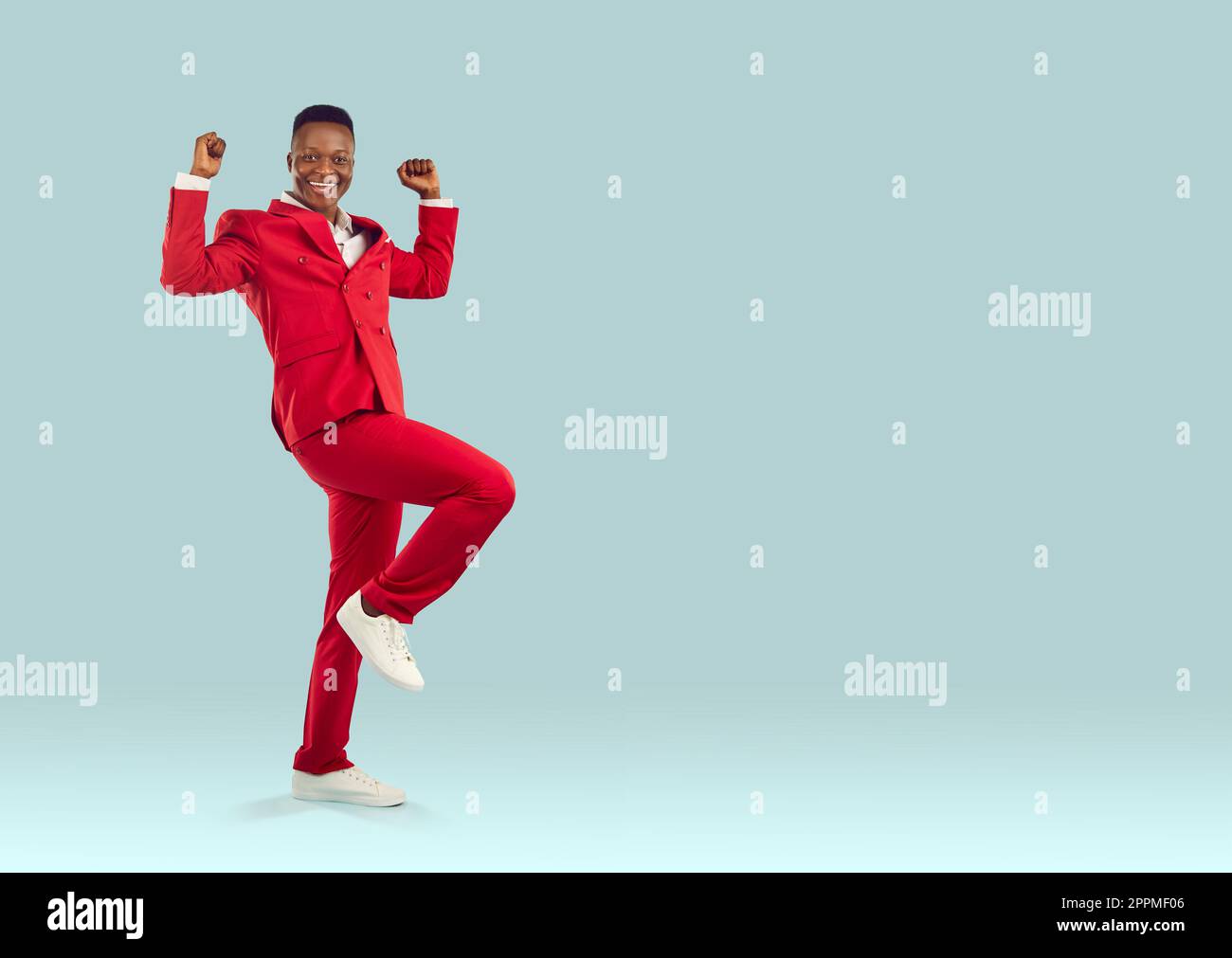 Glücklicher, stilvoller afroamerikanischer Mann freut sich aufrichtig über seinen Erfolg auf pastellfarbenem hellblauem Hintergrund Stockfoto