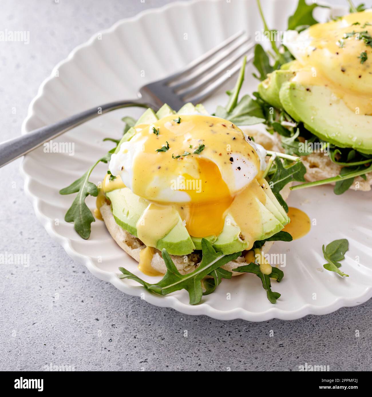 Gesundes Ei benedict Sandwich mit Avocado und Rucola, Frühstücksidee Stockfoto