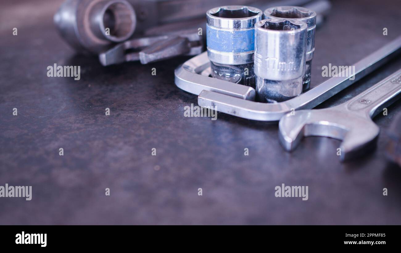 Handwerkzeuge bestehend aus Schraubenschlüsseln, Zangen, Steckschlüsseln, auf altem Stahlblechhintergrund angeordnet. Stockfoto