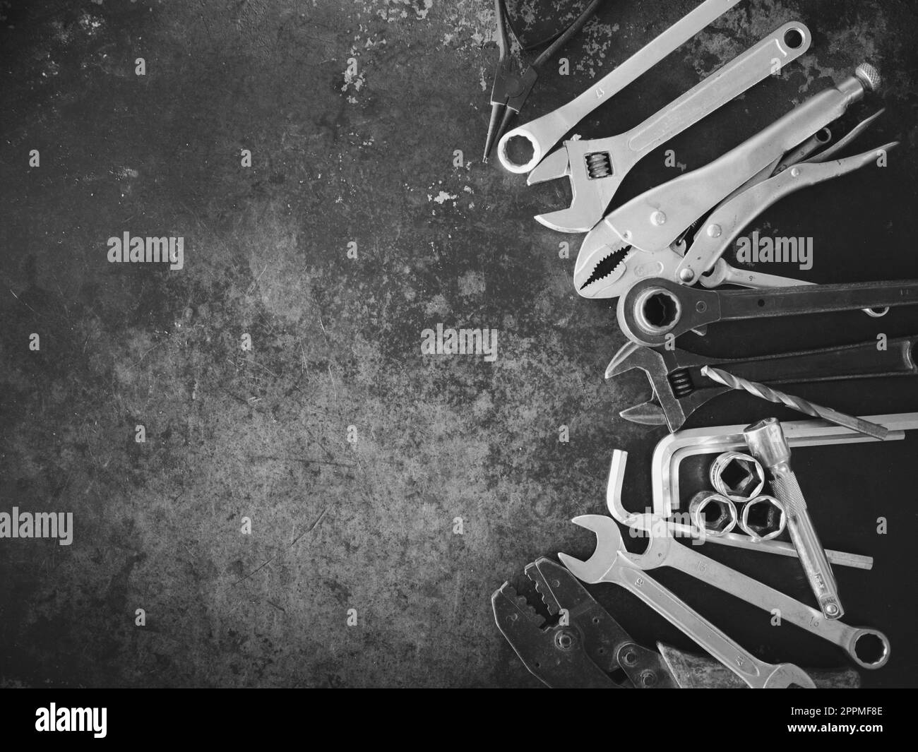 Handwerkzeuge bestehend aus Schraubenschlüsseln, Zangen, Steckschlüsseln, auf altem Stahlblechhintergrund angeordnet. Stockfoto