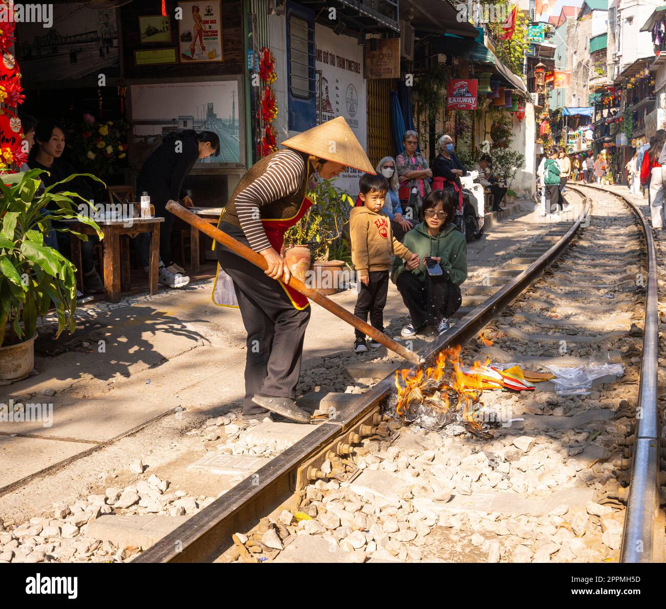 Eine Frau verbrennt Votivopfer für Vorfahren in Hanoi, Vietnam Stockfoto