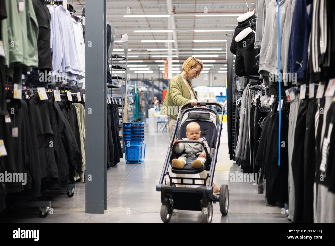 Lässig gekleidete Mutter, die in der Sportabteilung des Supermarkts  Sportschuhe und Bekleidungsartikel aussucht, mit ihrem kleinen Jungen im  Kinderwagen Stockfotografie - Alamy