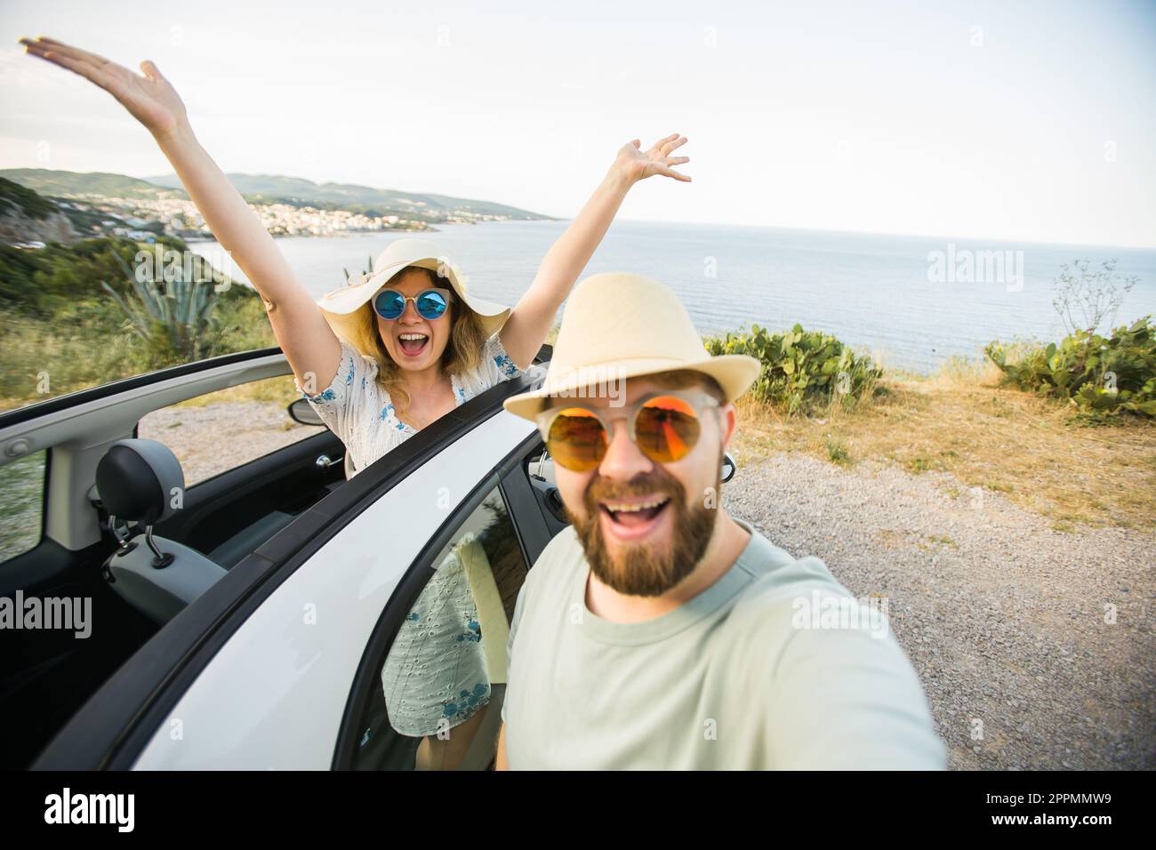 Romantisches Paar, das Selfie mit einer Smartphone-Kamera im Mietwagen Cabrio auf dem Meer oder am Strand macht, den Sommerurlaub zusammen genießt und an Wochenenden auf dem Handy am Meer ruht Stockfoto