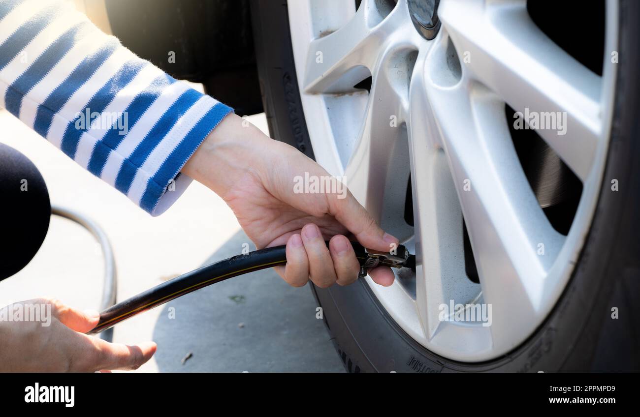 Die Frau pumpt den Reifen auf. Frau, die den Reifendruck prüft und Luft in den Reifen des Autorads pumpt. Autowartungsservice zur Sicherheit vor der Reise. Reifendruckpunkt. Füllluft im Autoreifen Stockfoto