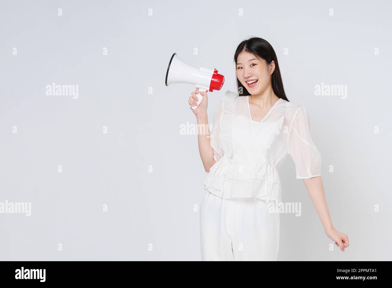 Junge Frau, die Megafon auf weißem Hintergrund isoliert hält. Stockfoto