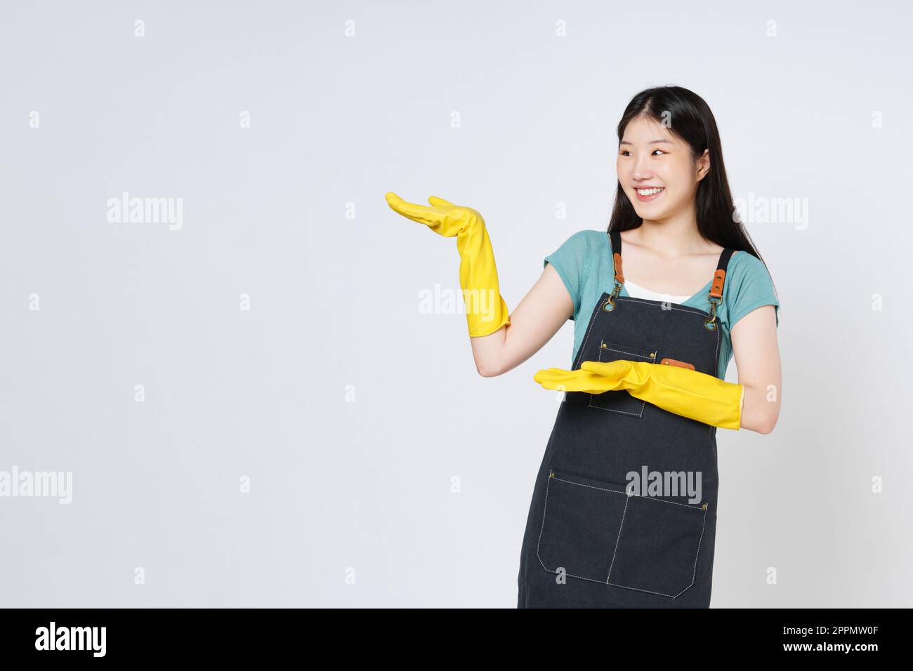 Junge Frau mit gelben Gummihandschuhen, die eine offene Handfläche mit einem auf weißem Hintergrund isolierten Kopierbereich für das Produkt zeigt. Stockfoto