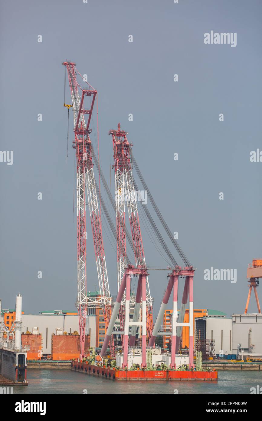 Massive Doppeldeckenkräne auf einem Boot, die Tandemheben für schwere Hebevorgänge in der Werft betreiben können. Vertikale Ansicht, Singapur. Stockfoto
