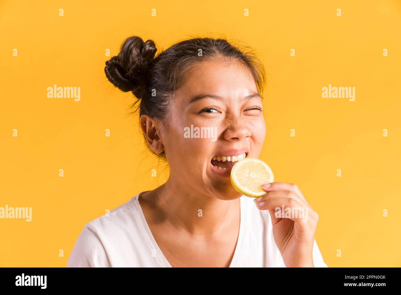 Frau beißt saure Zitrone in Scheiben Stockfoto