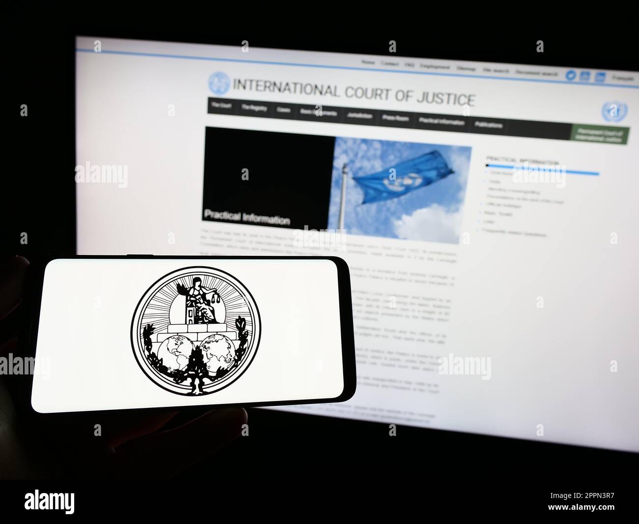 Person, die ein Smartphone mit dem Logo des Internationalen Gerichtshofs (IStGH) auf dem Bildschirm vor der Website hält. Konzentrieren Sie sich auf das Display des Telefons. Stockfoto