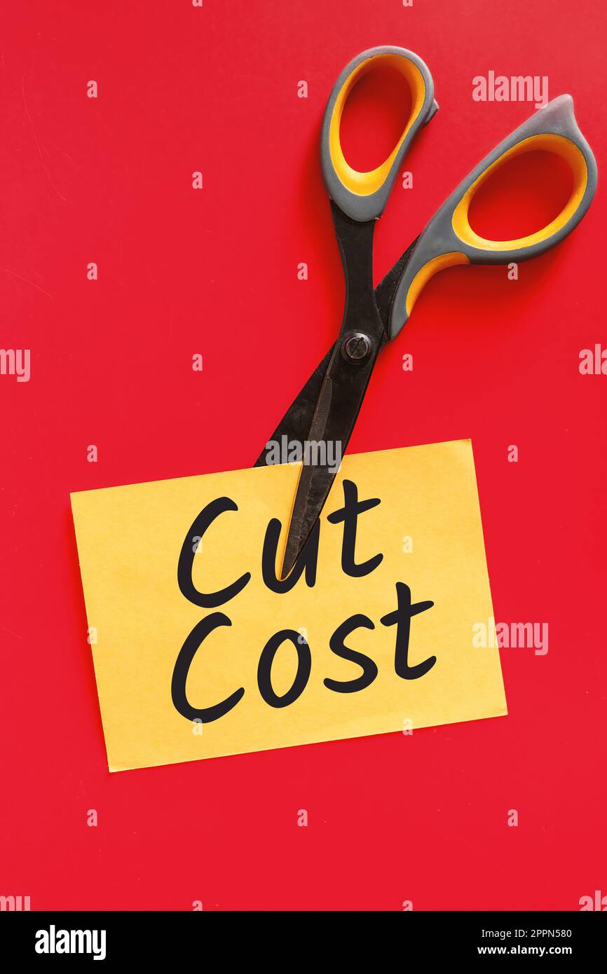 „Cost Cutting with Sissors and Sticky Note“ – Schere, die einen gelben Haftnotiz durchschneidet, um Kosten zu sparen. Stockfoto