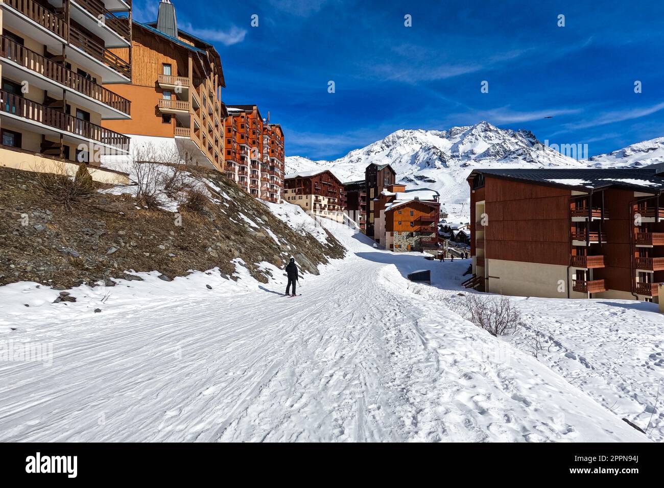Skipiste im Skigebiet Val Thorens in den französischen Alpen - schneebedeckte Strecke durch ein Dorf mit hölzernen Chalets im Trois Vallé Stockfoto