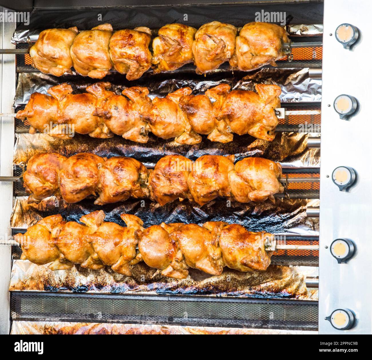 Eine Menge gebratene Hühner in einem großen Grill auf dem Oktoberfest in München gesehen Stockfoto