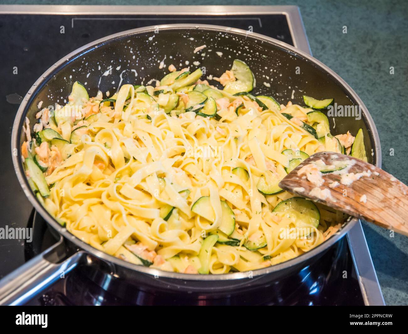 Zubereitung von Speisen mit Zucchini, Lachs und Pasta in einer Pfanne Stockfoto