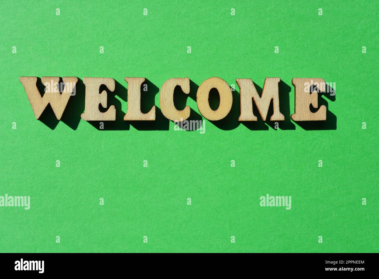 Willkommen, Wort in hölzernen Buchstaben isoliert auf hellgrünem Hintergrund Stockfoto