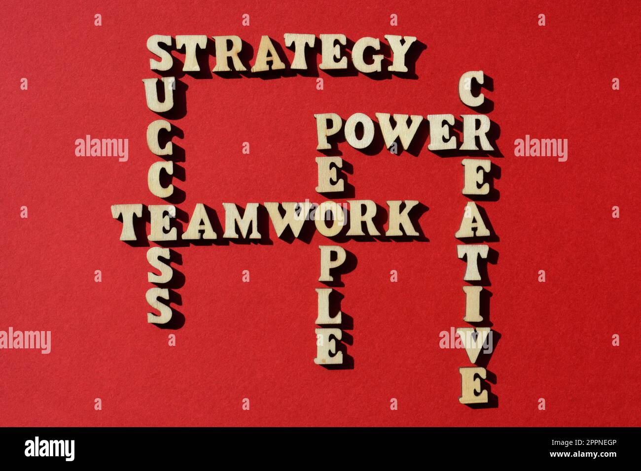Strategie, Erfolg, Teamwork, Mitarbeiterkraft, Kreativ, Wörter in hölzernen Buchstaben in Kreuzworträtselform isoliert auf rotem Hintergrund Stockfoto