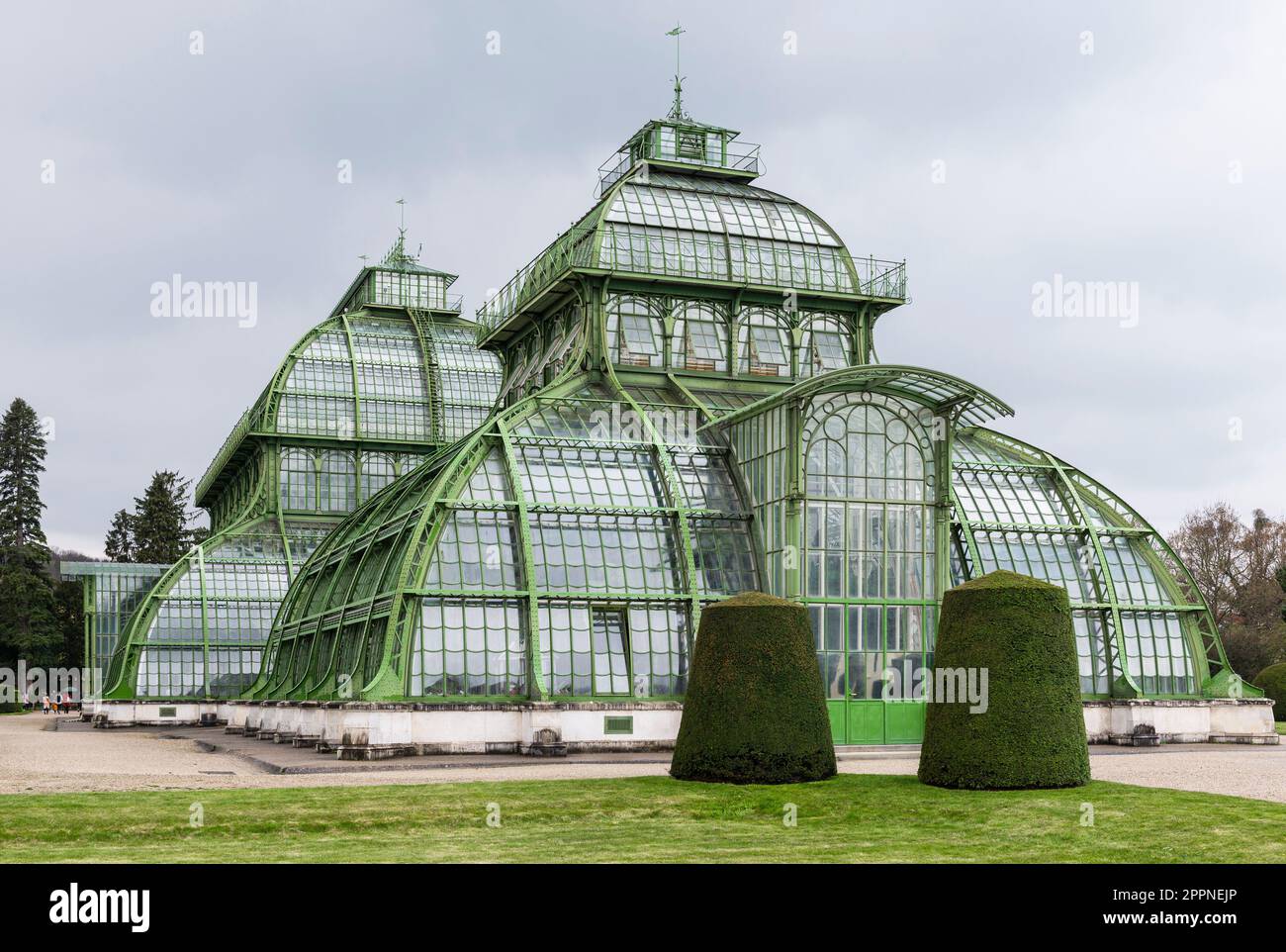 Die Kuppeln des Palmenhauses aus Schmiedeeisen, Gusseisen und Glas im Schlosspark Schönbrunn unter grauem Himmel, Wien, Österreich Stockfoto